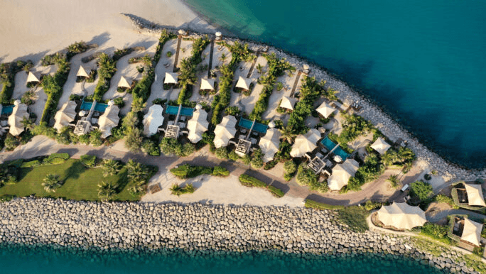 Tented beach villas along a rocky shore, seen from the air