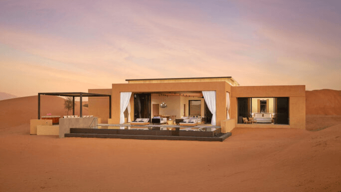 Private villa among red desert dunes at dusk