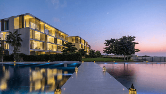 Low-rise resort building beside a reflecting pool at dusk