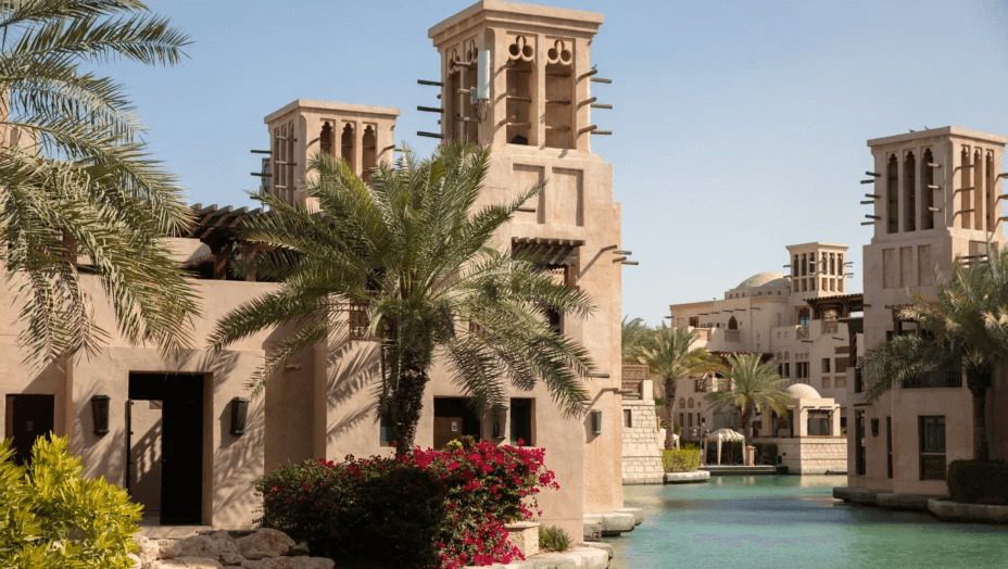 Wind-tower summer houses beside a palm-lined waterway